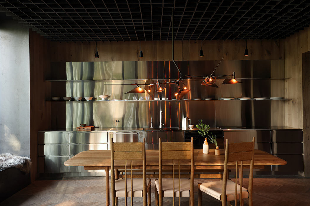 A modern, minimalist kitchen with a wooden table, shelves, and pendant lighting.