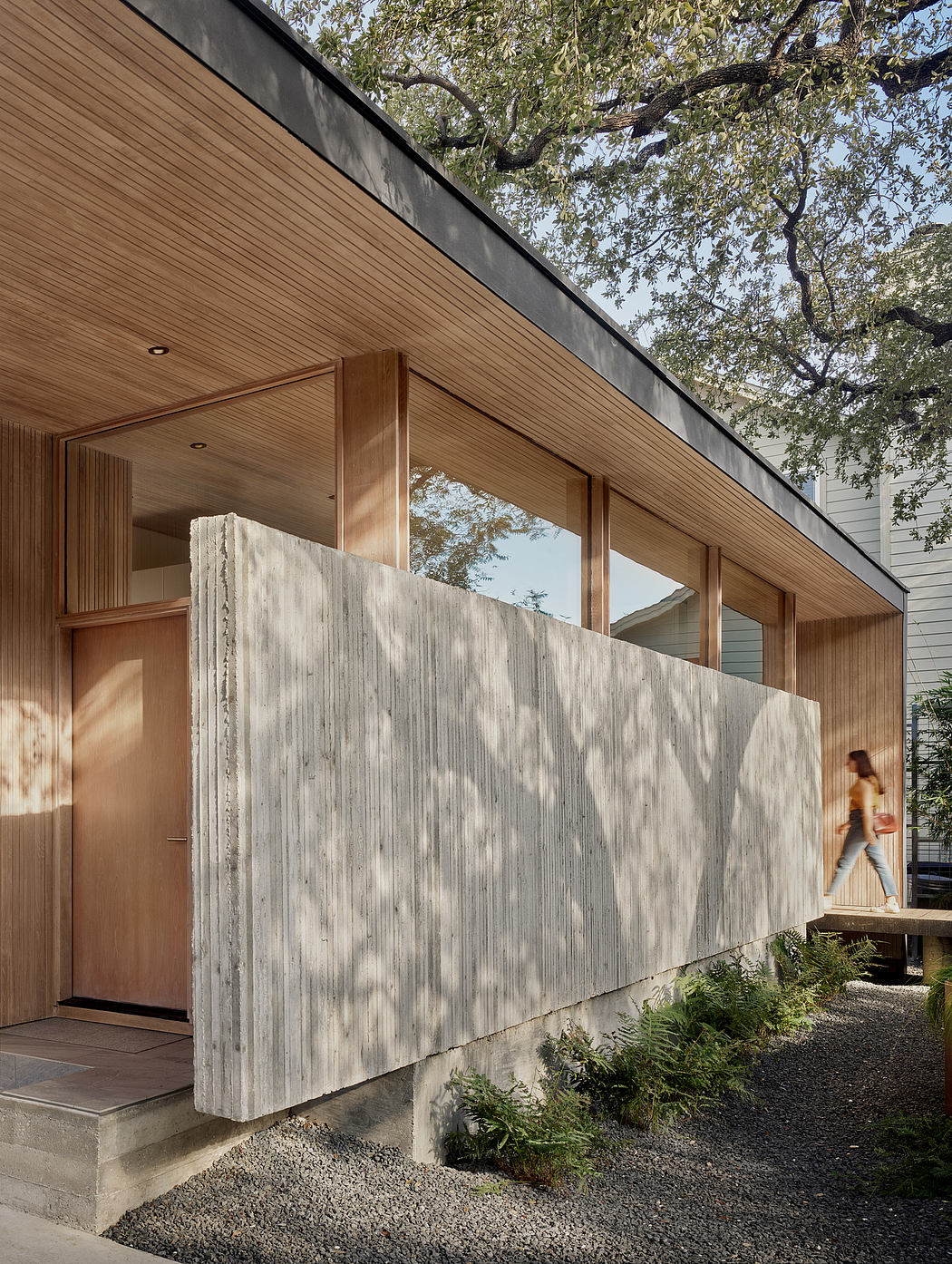 A modern home with a wooden facade, large windows, and a concrete wall feature.
