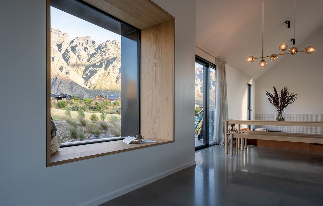 Expansive window frame showcases dramatic mountainous landscape beyond contemporary interior.