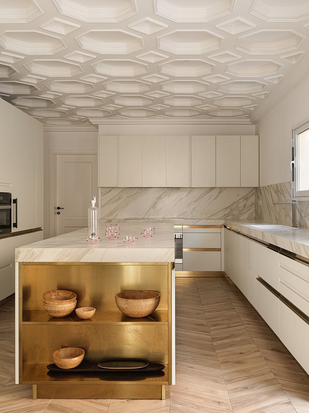 Elaborate geometric ceiling, marble countertops, gold accents, and wood cabinets in elegant kitchen.