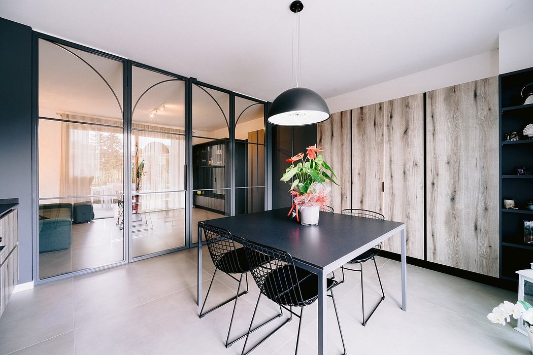 Large black metal-framed windows, wooden walls, and a modern black dining table with chairs.