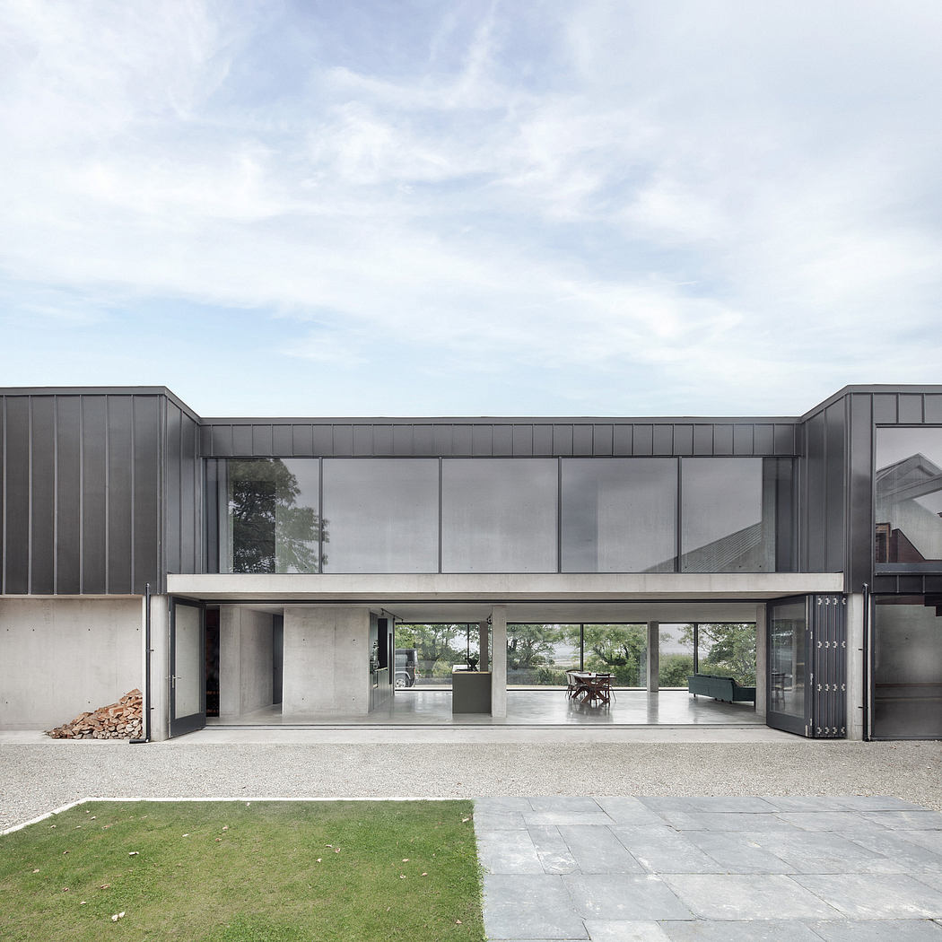 The modern building features a minimalist design with sleek glass walls, concrete exterior, and lush landscaping.