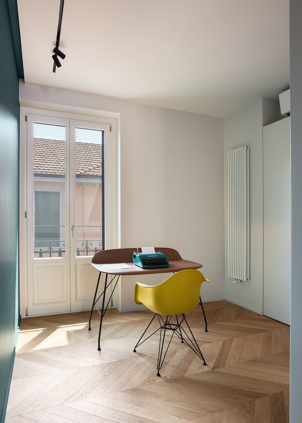 Cozy home office with a wooden desk, yellow chair, and herringbone wood flooring.