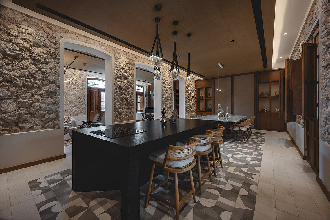 A modern, rustic kitchen with stone walls, black countertops, and patterned tile flooring.