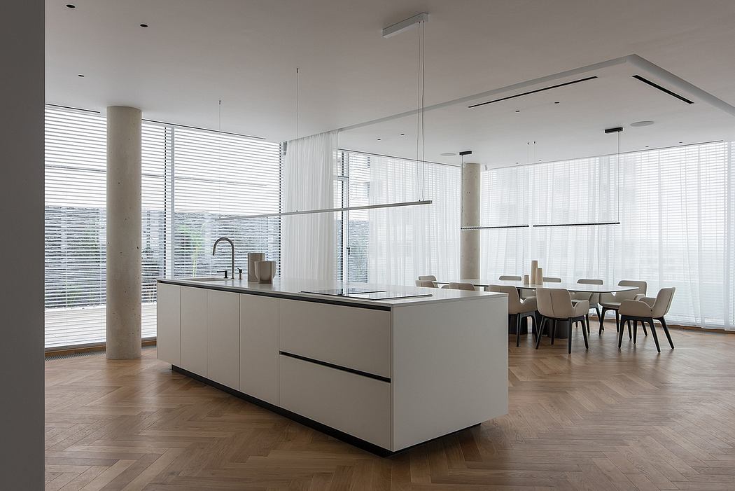 Minimalist kitchen with sleek cabinetry, large windows, and a wooden dining area.