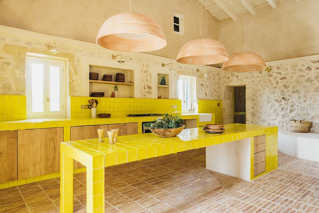 Bright, modern kitchen with yellow tile countertops and wooden cabinetry, stone walls, and hanging lamps.