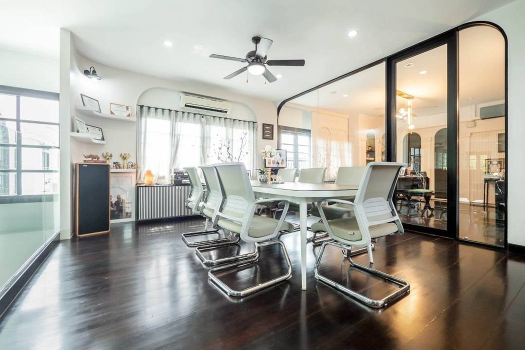 A modern open-concept dining area with a sleek table, ergonomic chairs, and a large mirror wall.