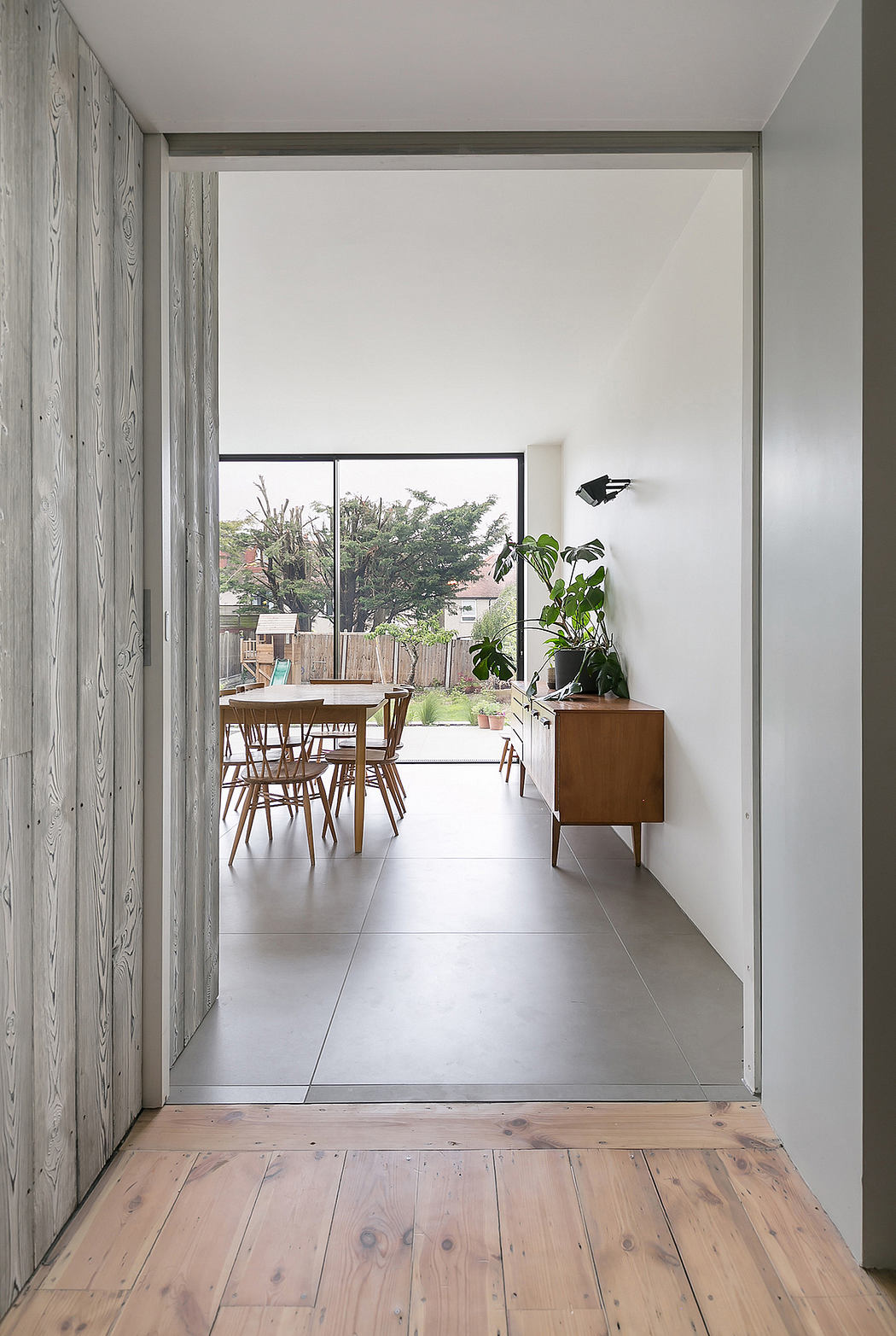 A minimalist interior with wooden floors, white walls, and a wooden dining table set.