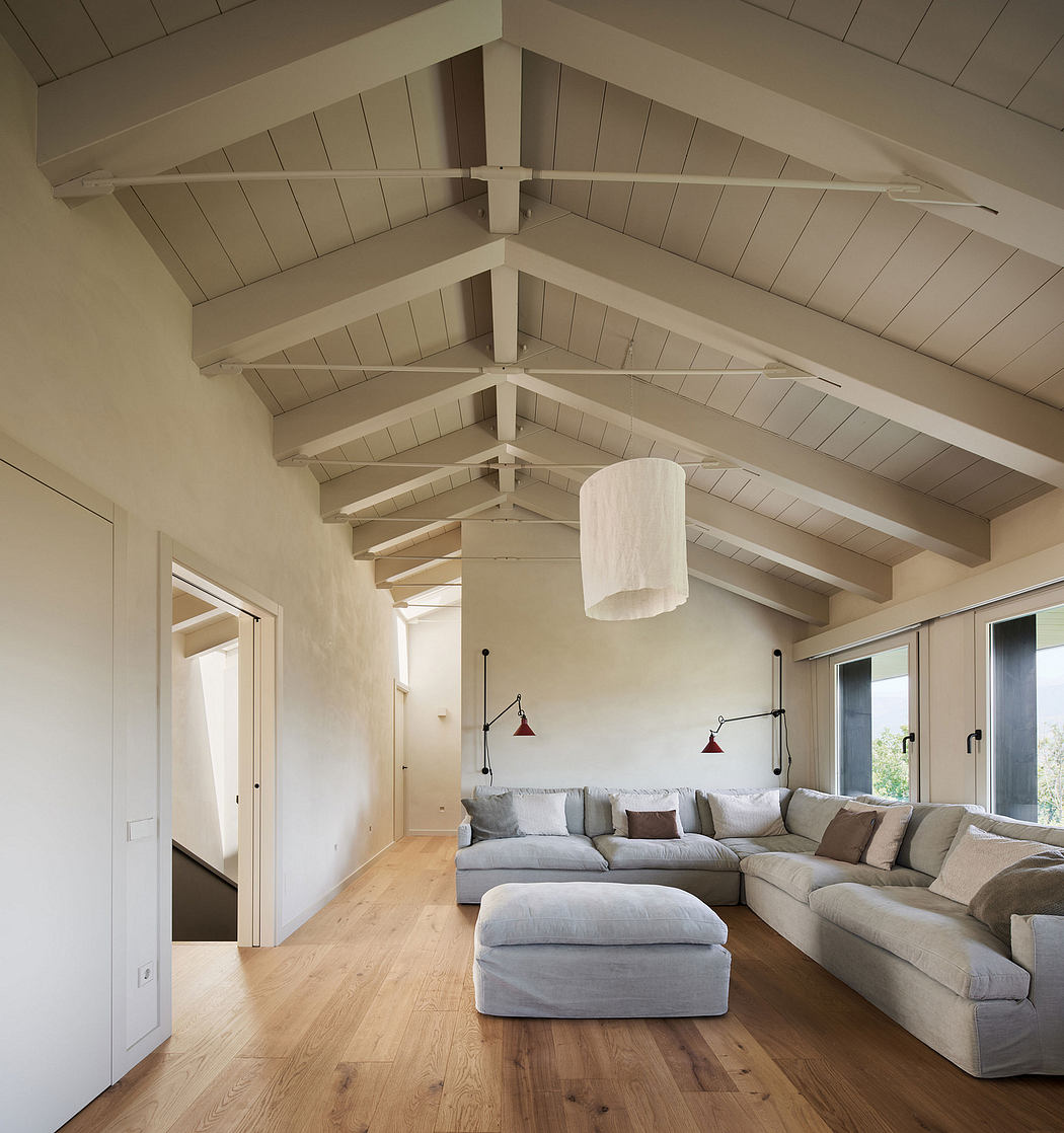 Modern, open-concept living room with vaulted ceiling, exposed wood beams, and neutral furnishings.