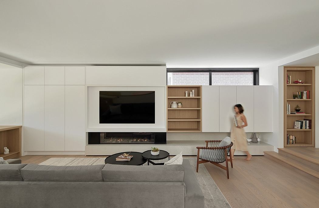 Minimalist living room with built-in TV unit, shelving, and a cozy gray sofa.