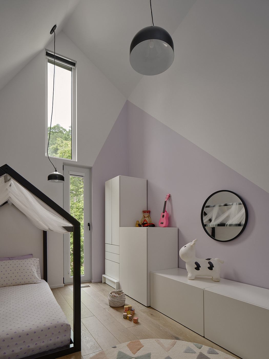 Airy bedroom with slanted ceilings, modern pendant light, and built-in storage.