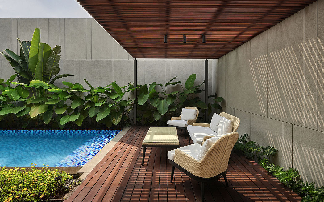 Elegant outdoor patio with lush greenery, tiled pool, and cozy seating area.