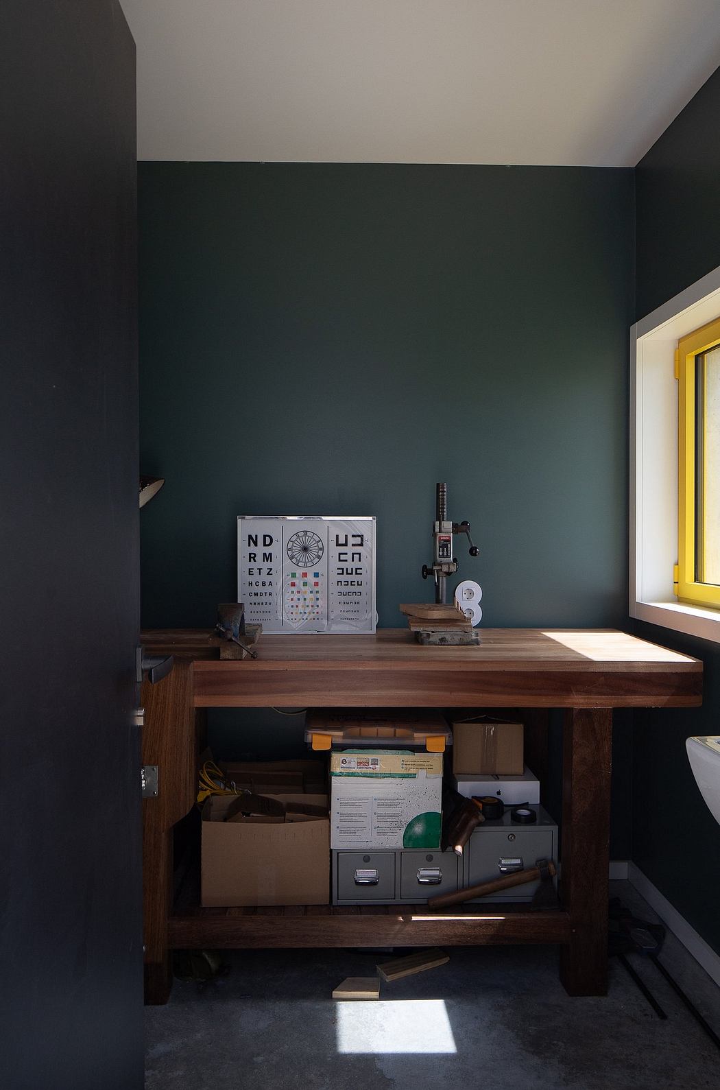Dark, minimalist room with a wooden workbench and eye exam charts on the wall.