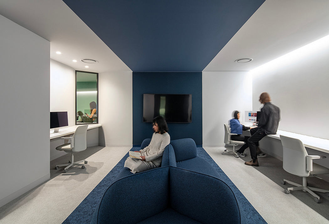 Open-concept office with modern, minimalist design, featuring blue and gray color scheme, comfortable seating, and integrated workstations.