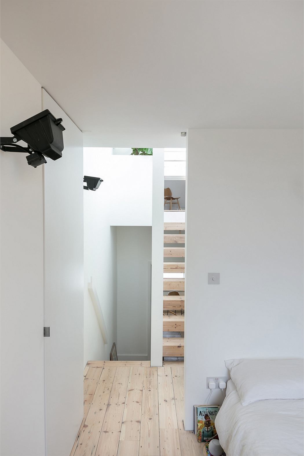 Modern minimalist interior with wood flooring, glass wall, and wall-mounted lights.