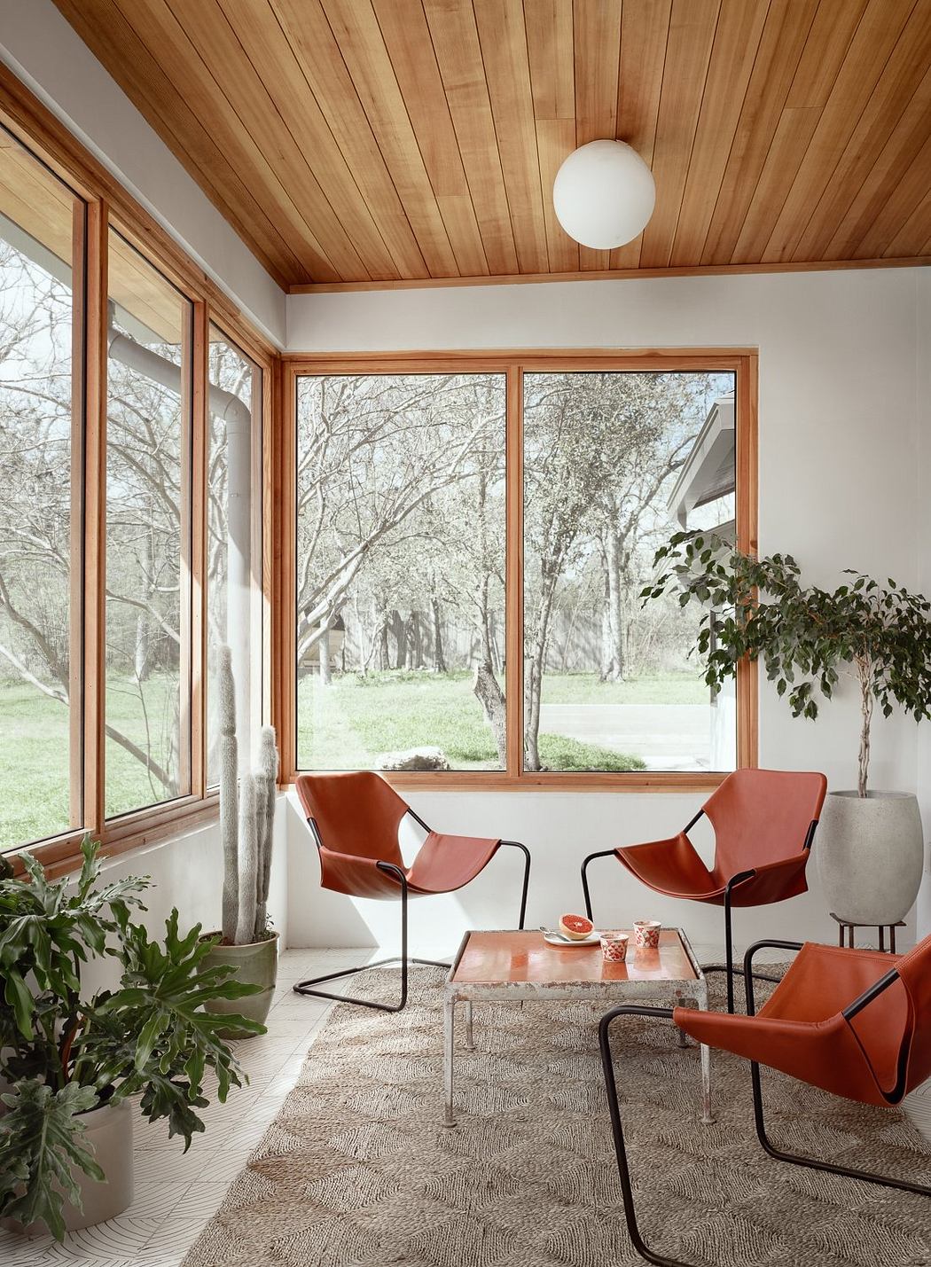 Cozy, modern cabin interior with wooden walls, large windows, and mid-century furniture.