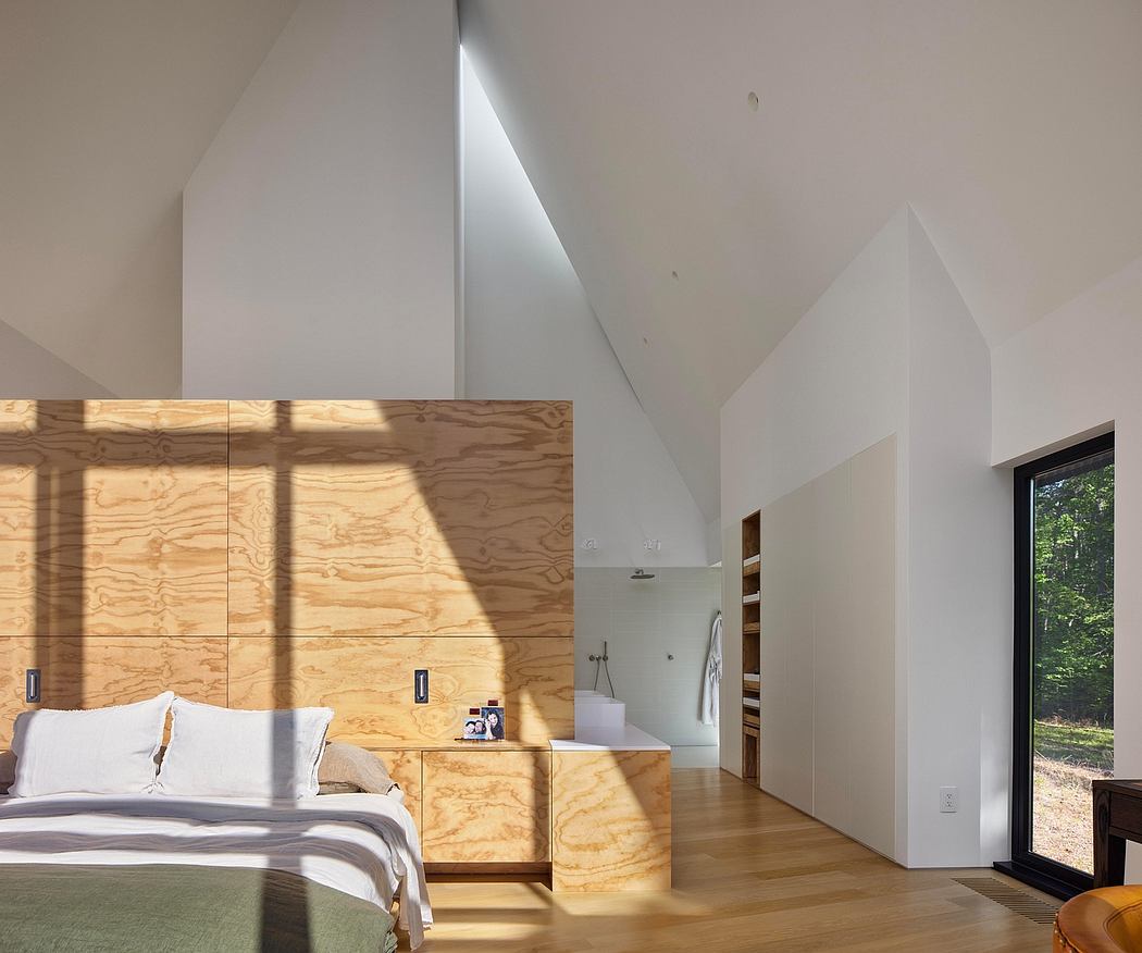 Minimalist bedroom with plywood wall panels, vaulted ceilings, and a view to the outdoors.