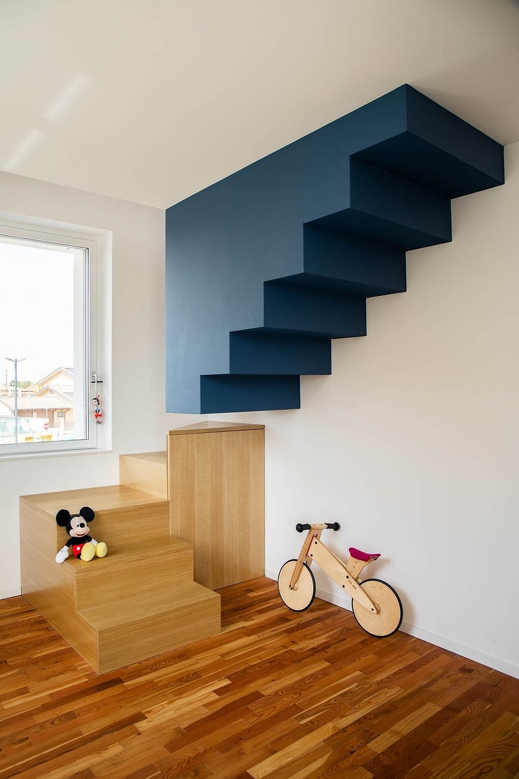 A modern staircase design with floating wooden steps and a dark blue accent wall.