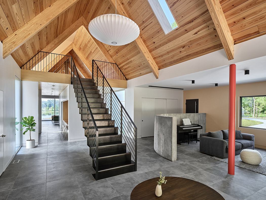 Spacious, modern interior with vaulted wood ceiling, metallic staircase, and minimalist furniture.