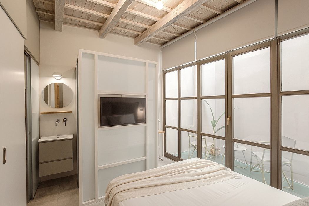 Cozy modern bedroom with wooden ceiling beams, large windows, and a minimalist vanity.