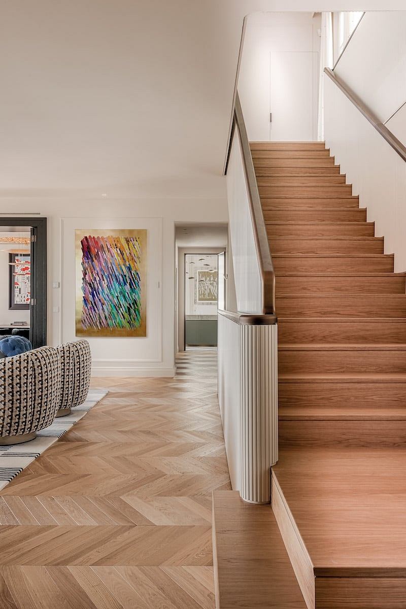 Elegant wooden staircase with modern art decor in stylish interior space.