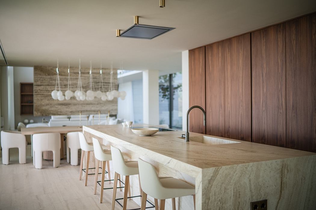 A modern, minimalist kitchen with a wooden counter, pendant lights, and white chairs.