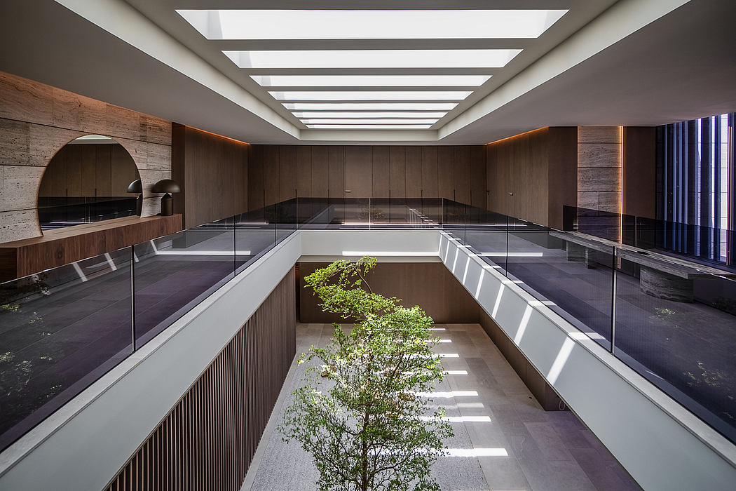 A modern and minimalist interior design with clean lines, glass walls, and a small tree.