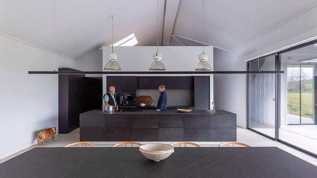Sleek, modern kitchen with black cabinetry, pendant lights, and large sliding glass doors.