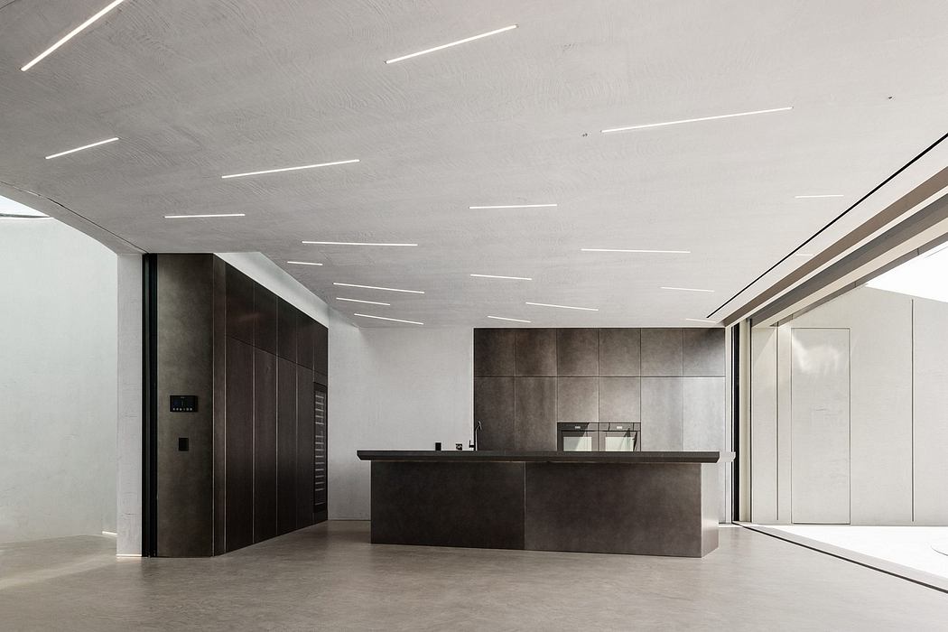 Minimalist office space with sleek concrete walls, suspended linear lighting, and a dark reception desk.