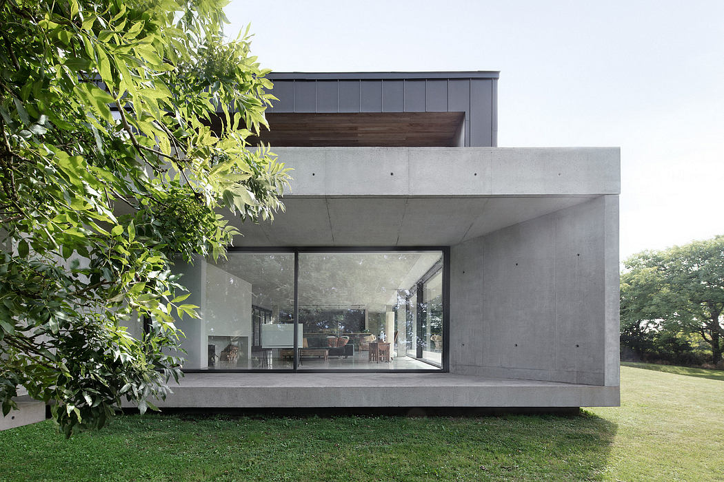 Contemporary concrete and wooden structure with expansive glass windows overlooking a grassy yard.