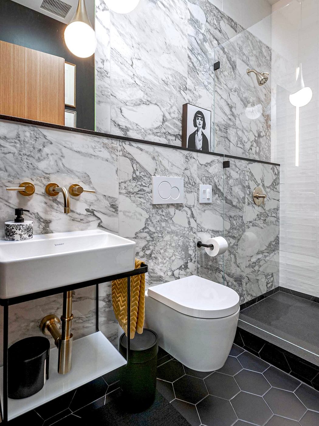 A modern bathroom with marble walls, gold fixtures, and a geometric tile floor.