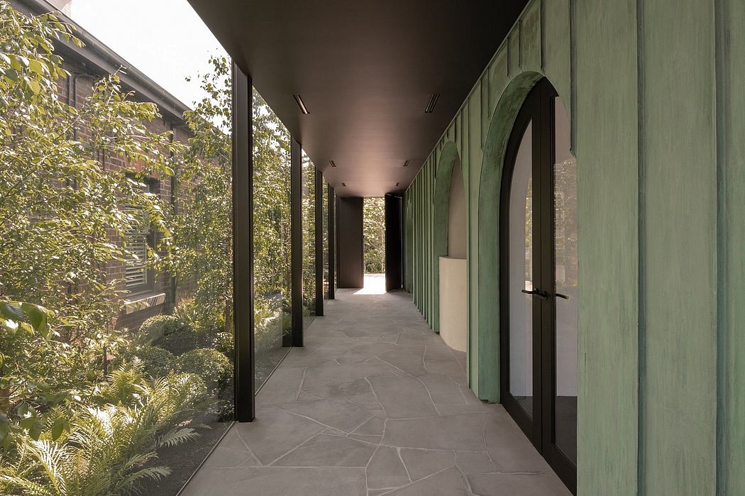 Spacious hallway with stone floor, green arched entryways, and lush garden views.