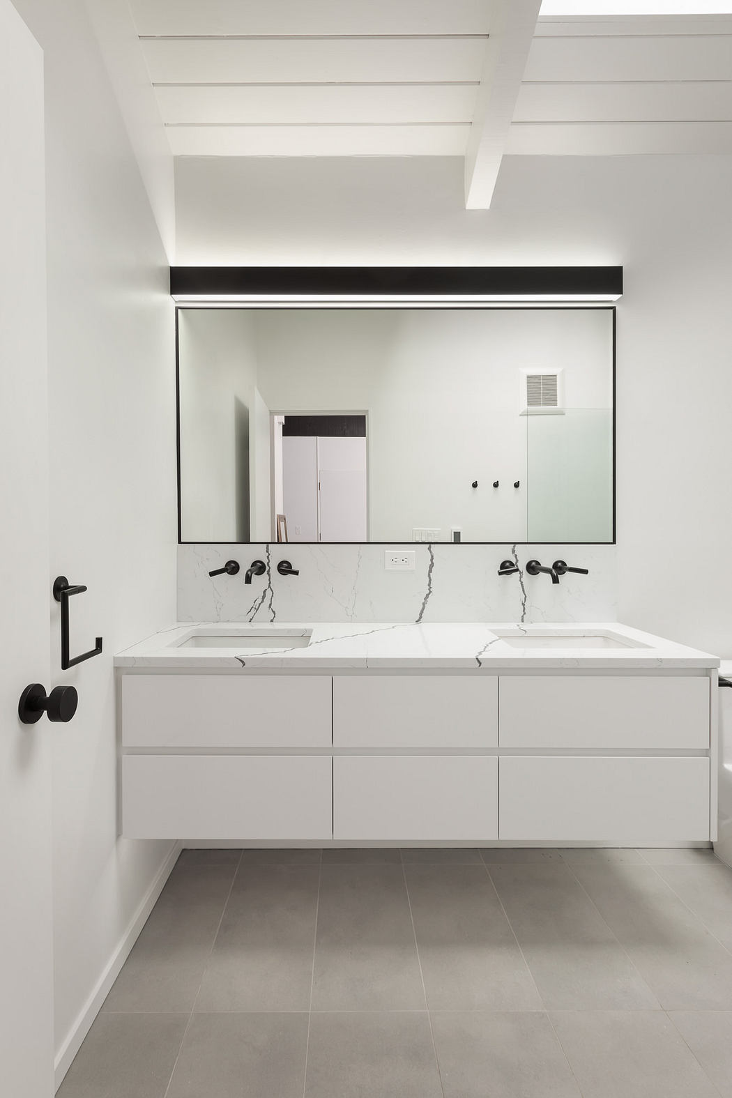 A modern, minimalist bathroom with a sleek, white vanity and marble countertop.