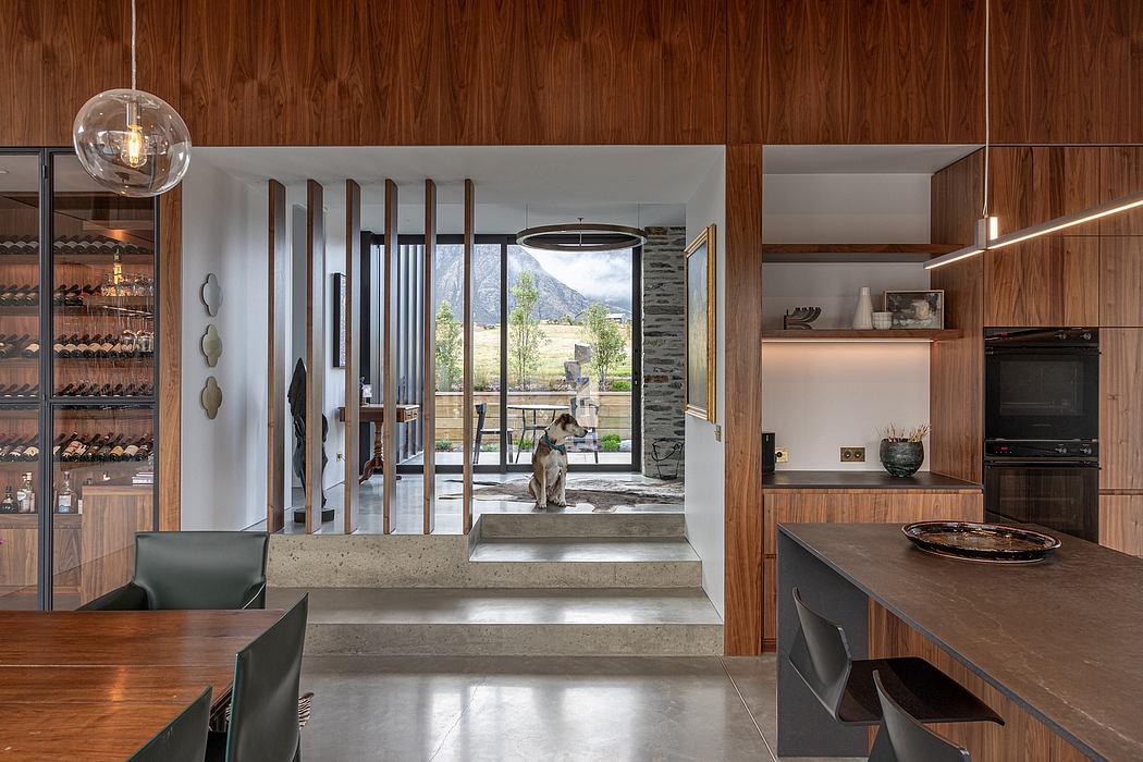 Modern open-concept kitchen and living area with wooden walls, sleek furniture, and mountain view.