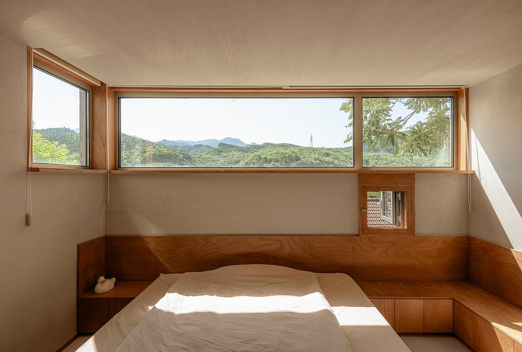 A cozy bedroom with large windows showcasing a lush, mountainous landscape outside.