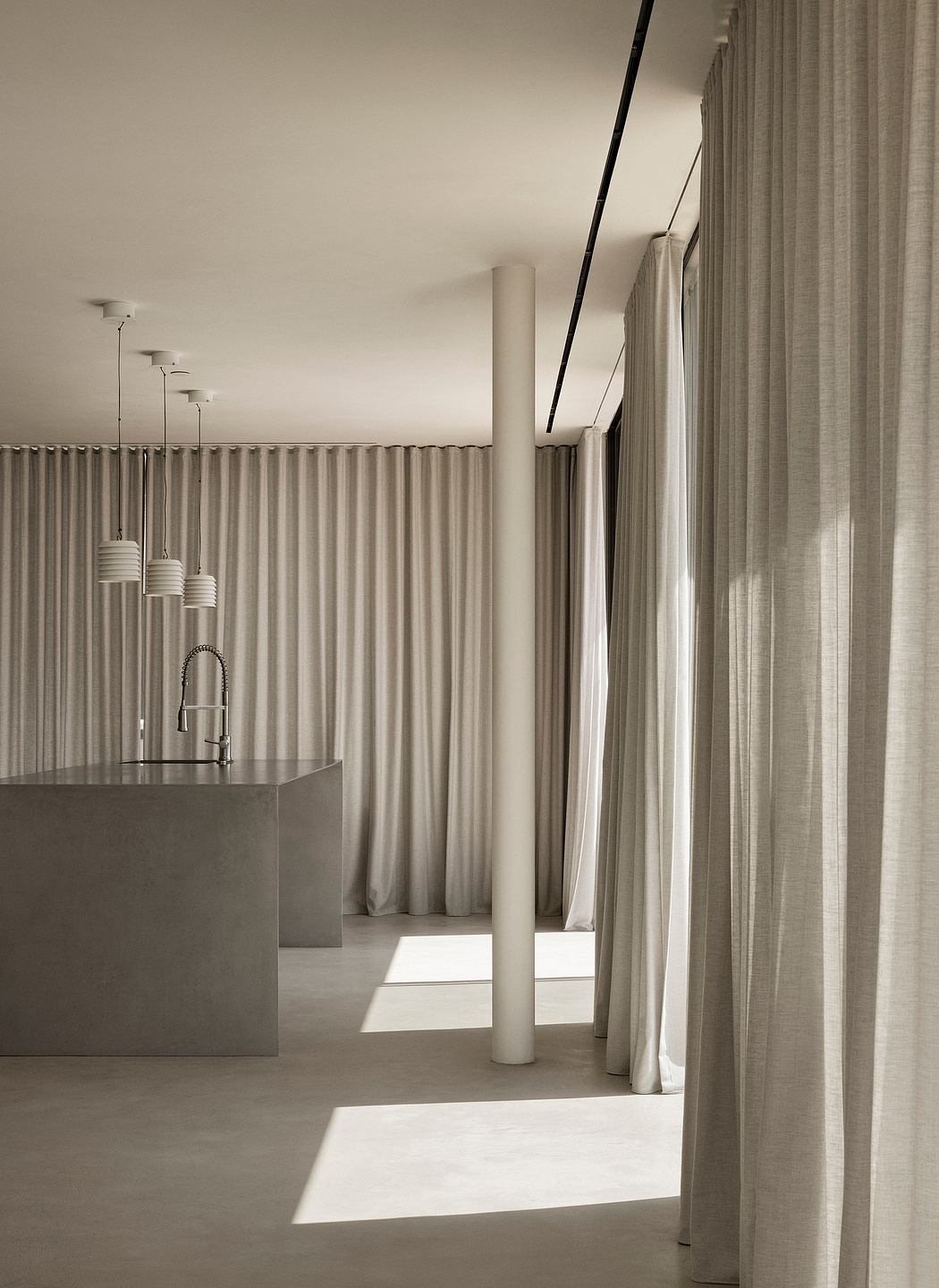 Modern minimalist kitchen with pendant lights, curtained alcove, and sleek counter.