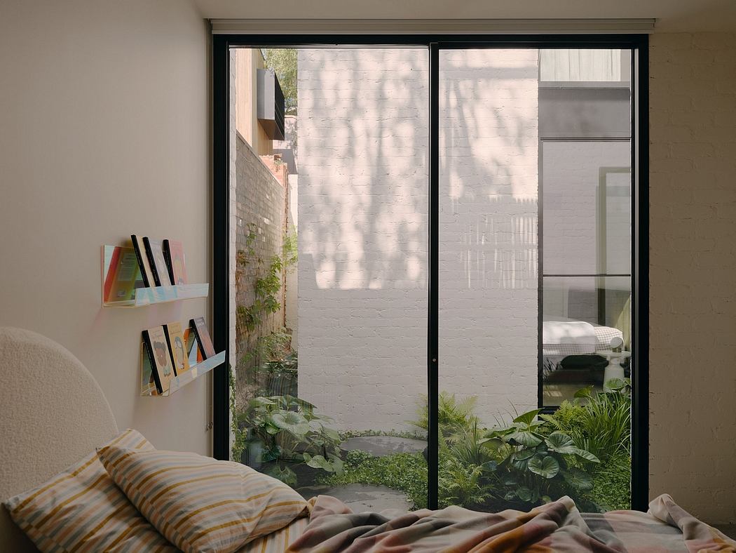 Cozy bedroom with minimalist décor, lush greenery visible through floor-to-ceiling windows.