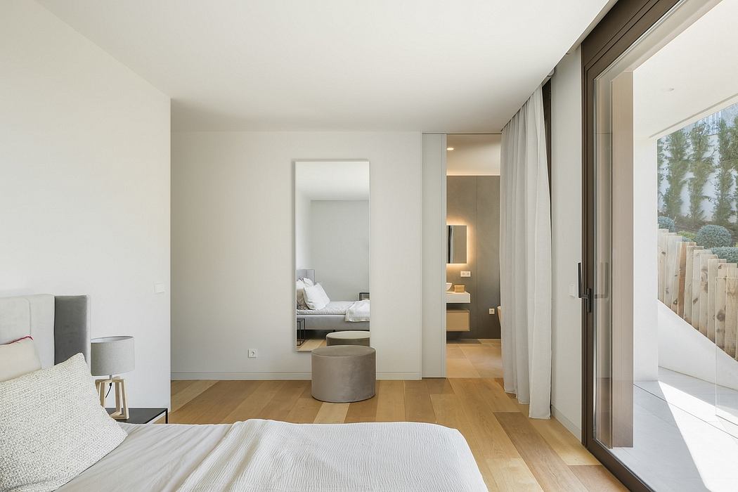Spacious and minimalist bedroom with en-suite bathroom, floor-to-ceiling windows, and hardwood floors.