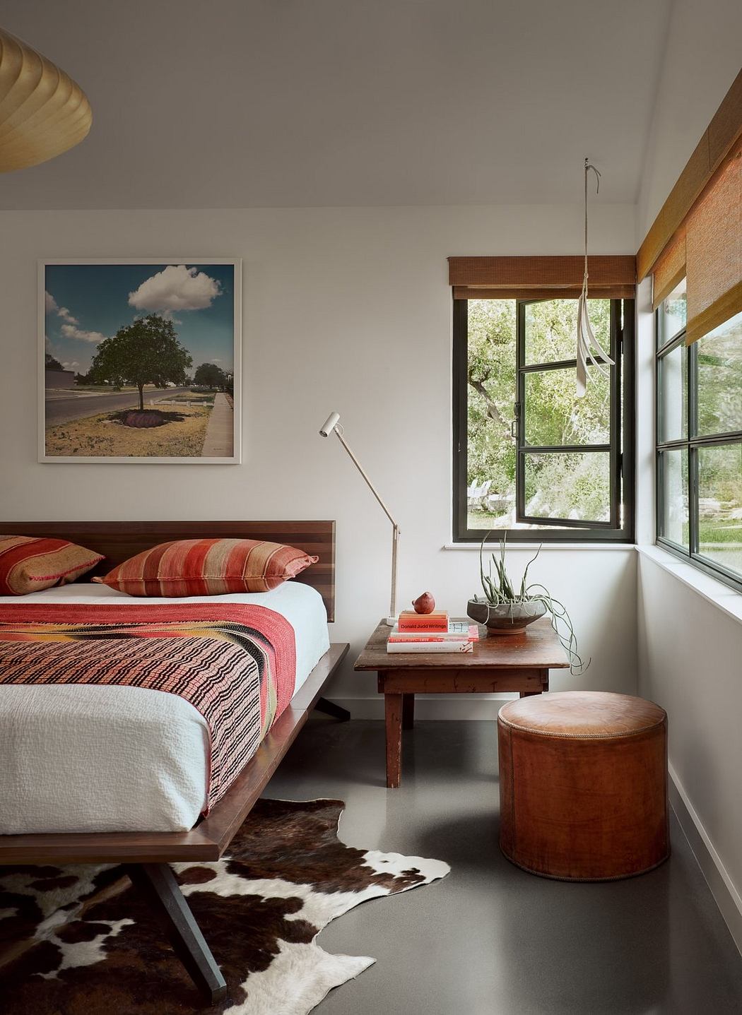 Cozy bedroom with wooden furniture, rustic accents, and a large window overlooking nature.