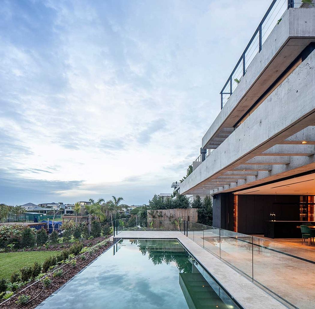 Sleek, modern house with striking concrete and glass facade, infinity pool, and lush greenery.