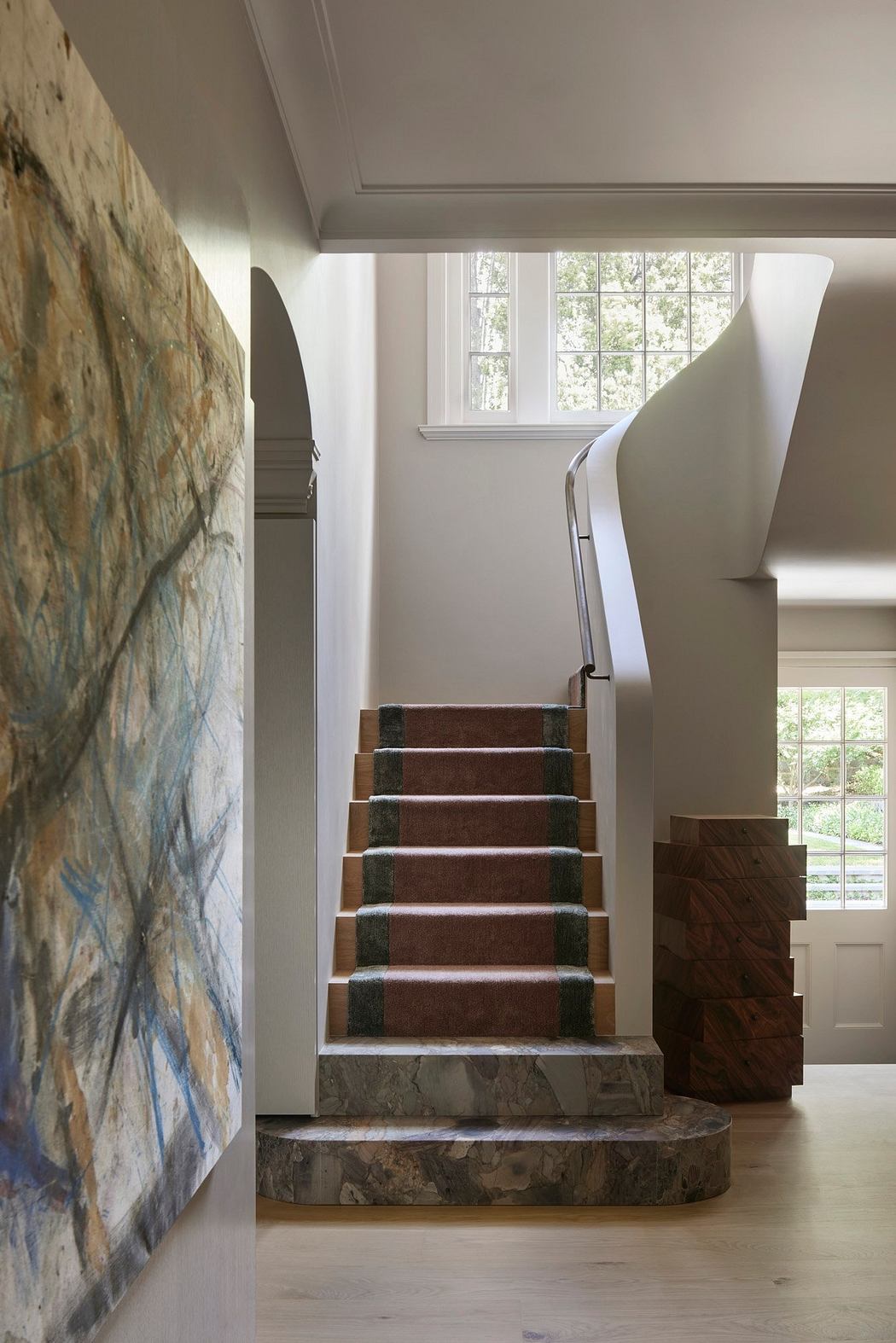 Striking stone staircase with wooden treads and modern handrail in spacious interior.