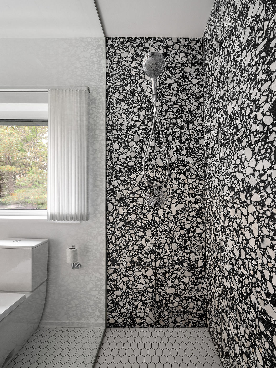 Striking black-and-white patterned tile walls and hexagonal floor tiles in a modern bathroom.