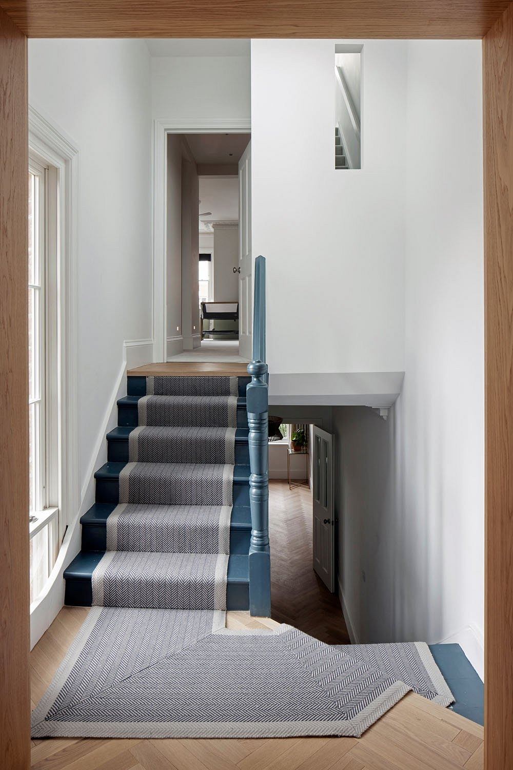 Elegant staircase with patterned gray carpet and blue wooden accents, leading to interior spaces.