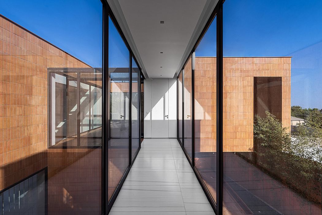 Modern architectural corridor with expansive glass windows and warm-toned tiled walls.