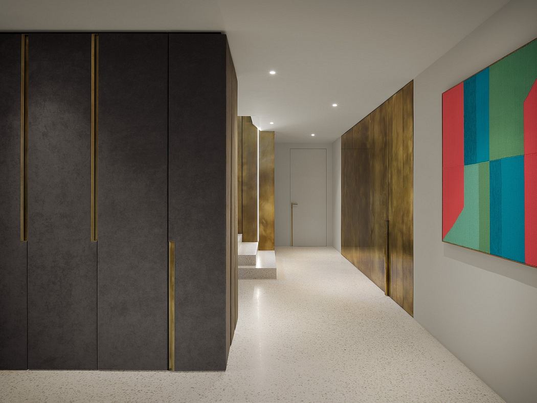 A modern, minimalist hallway with black and gold cabinets, colorful artwork, and terrazzo flooring.