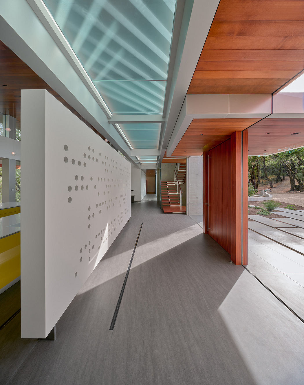 A modern, open-plan interior with a glass ceiling, wooden accents, and a patterned wall.