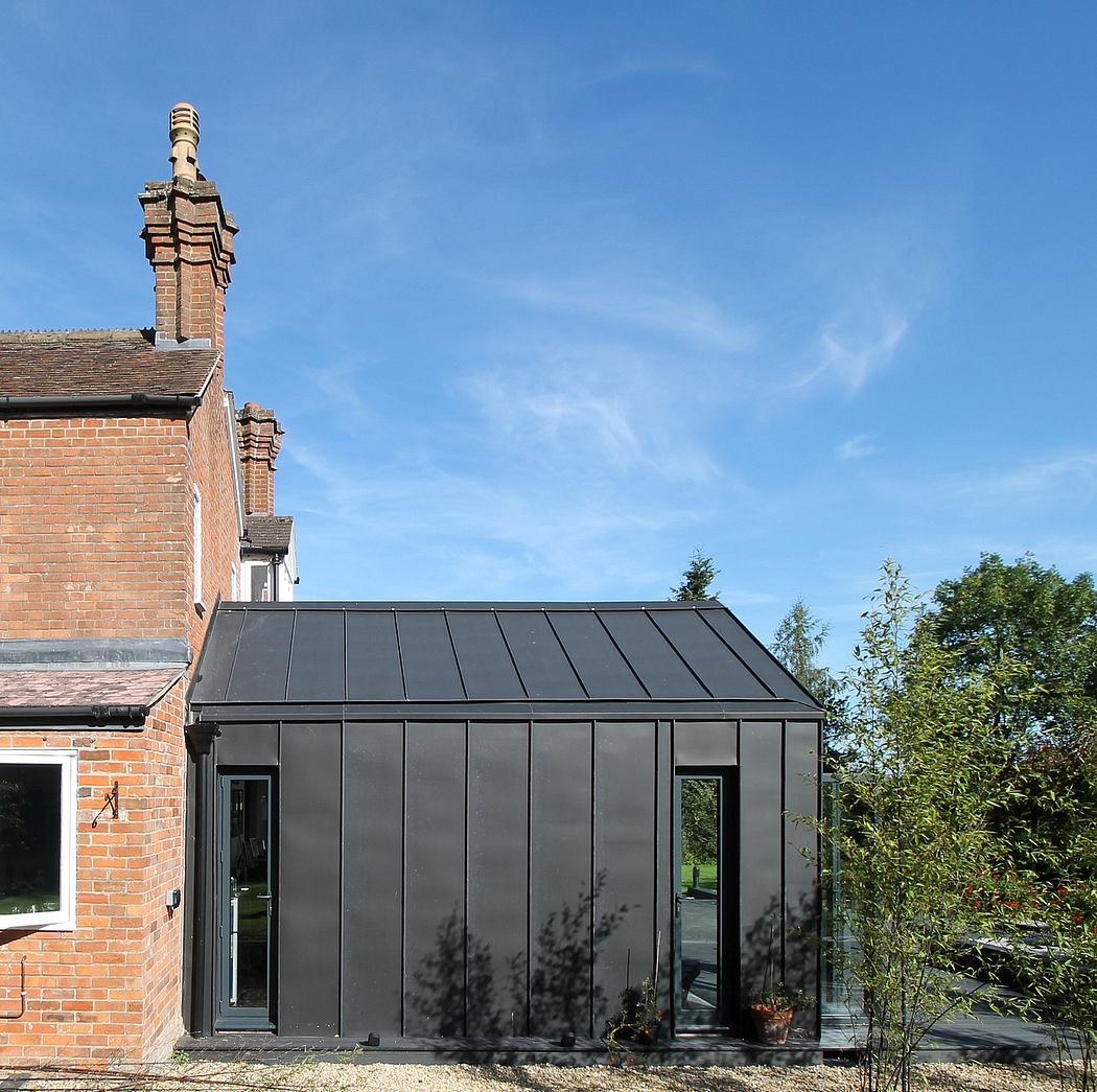 Brick building with sleek black glass extension and pitched slate roof.