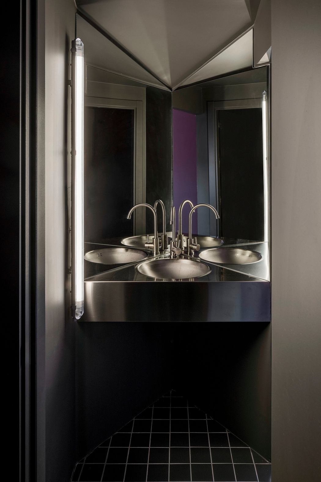 Sleek, modern bathroom design with a metallic sink and vanity, dramatic lighting, and geometric patterns.