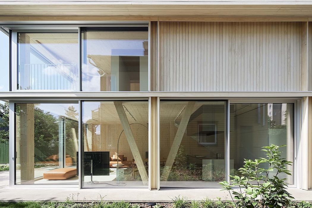Large glass walls, wooden beams, and lush greenery in a modern architectural design.