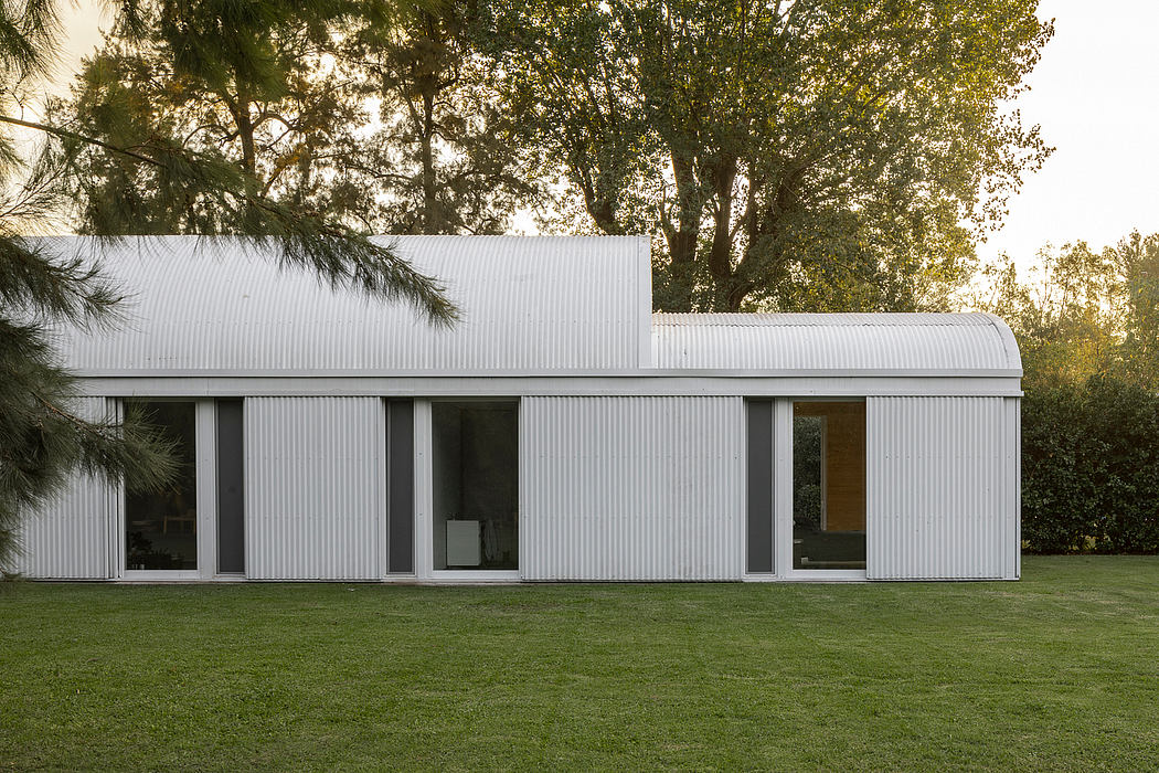 A modern, minimalist building with large windows set against a lush, green landscape.